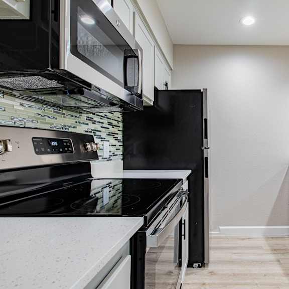 a modern kitchen with black appliances and white countertops at sofia apartments, tempe, 85283