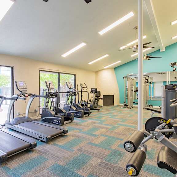 the gym with cardio equipment at the community center apartments