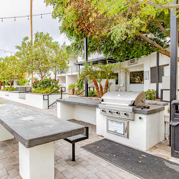 a patio with a barbecue grill and a table with benches