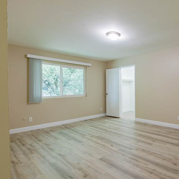 an empty living room with wood floors and a window