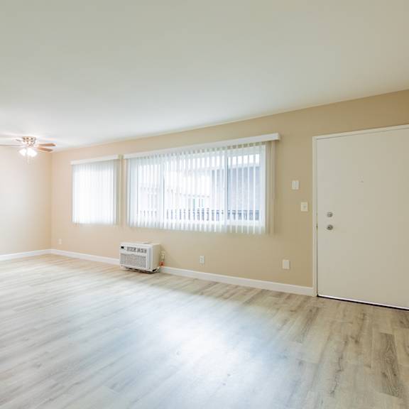 an empty living room with wood floors and a window