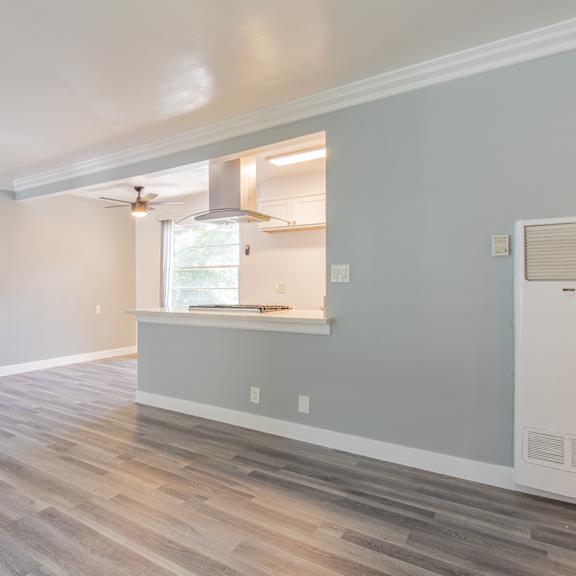 an empty living room with a window and a kitchen