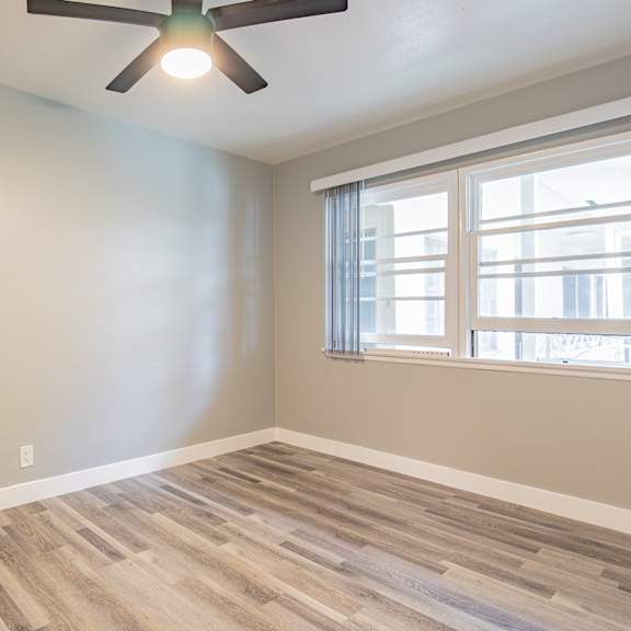 an empty room with a ceiling fan and a window