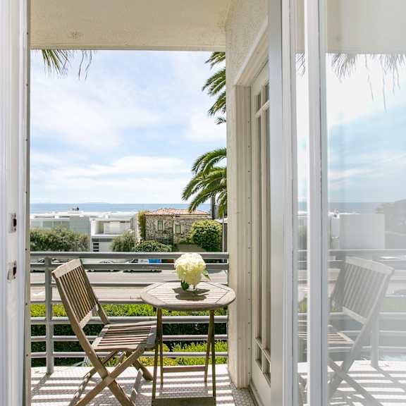 a balcony with a table and chairs and a view of the ocean