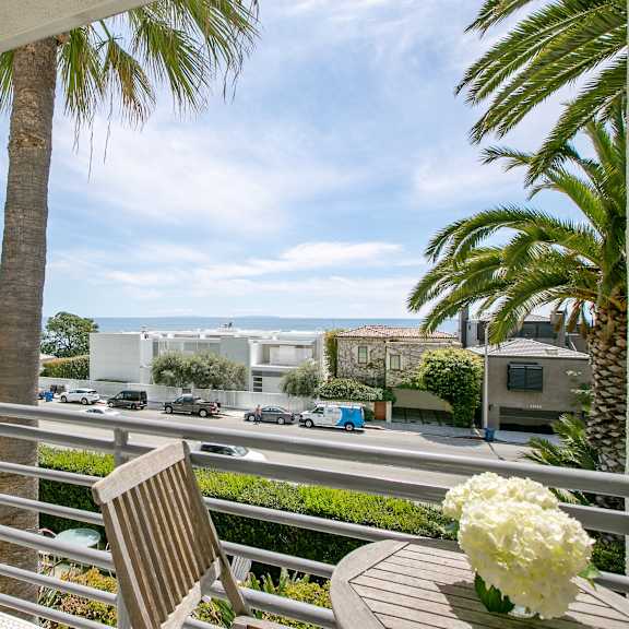a balcony with a table and a chair and palm trees