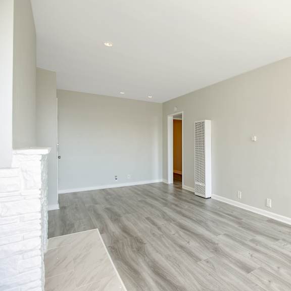 an empty living room with wood flooring and white walls