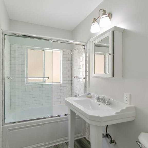 a white bathroom with a sink and a shower