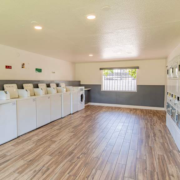 a community laundry room with washers and dryers and a wood floor
