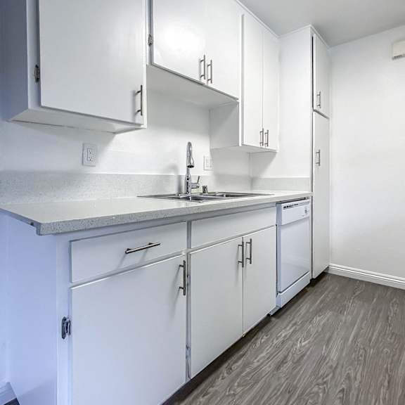 a kitchen with white cabinets and a grey counter top.