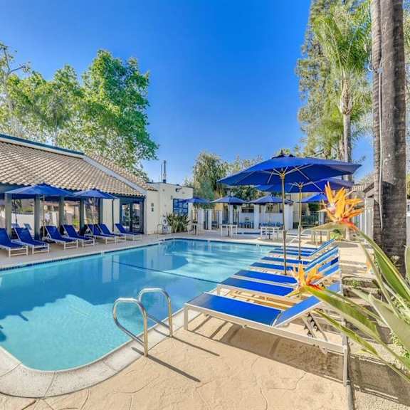 a swimming pool with blue chairs and umbrellas