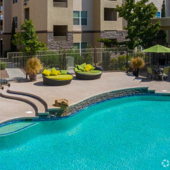 a resort style pool with lounge chairs and umbrellas