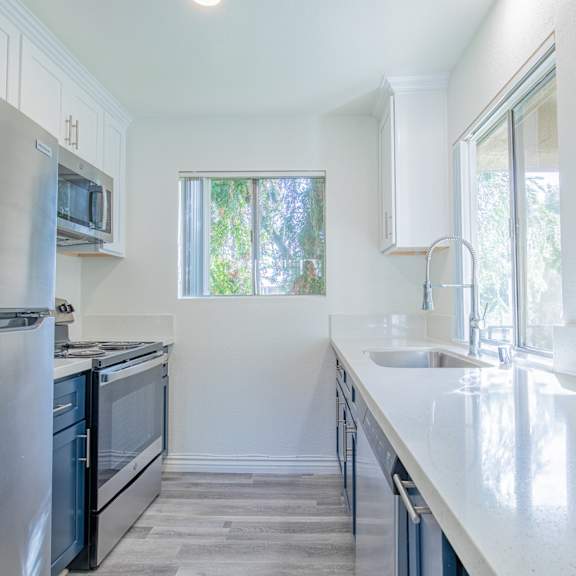 a modern kitchen with stainless steel appliances and white countertops.