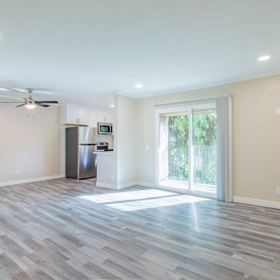a spacious room with a ceiling fan and a refrigerator.