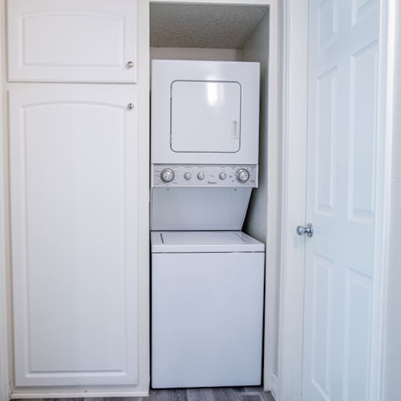 a white washing machine is in a small laundry room.