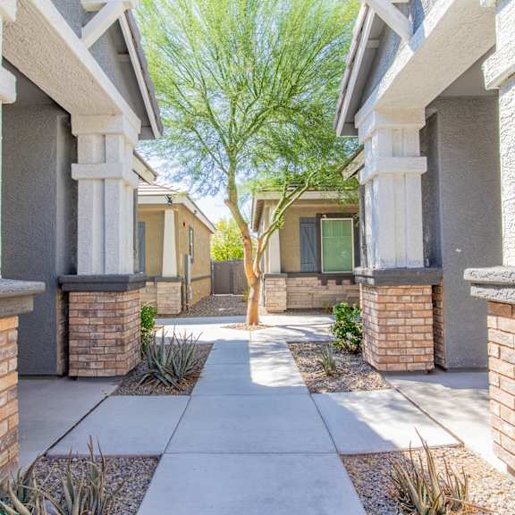 a walkway between two buildings with a tree in the middle at villas on olive, peoria, arizona