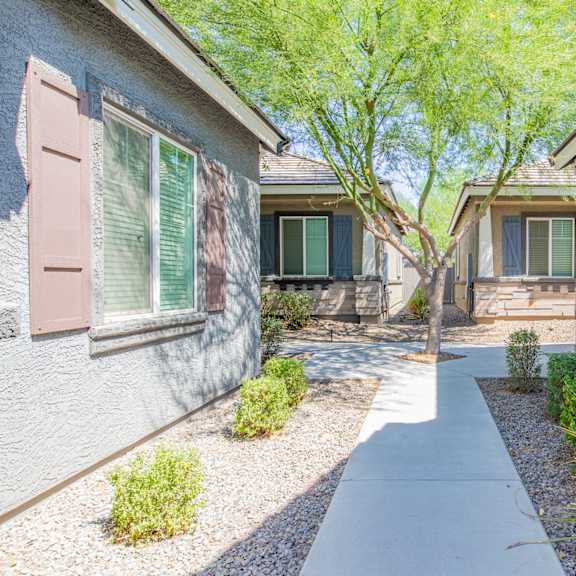 a walkway between two houses with trees and plants at villas on olive, peoria, az 85345