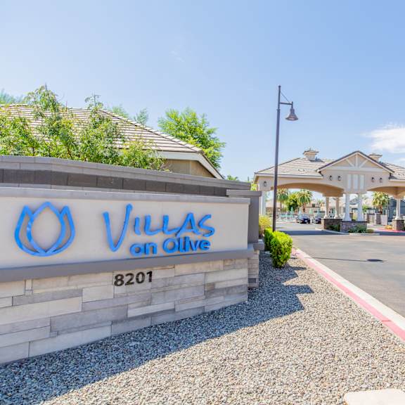 a villas on olive apartments entrance with a sign and palm trees at villas on olive, peoria, arizona