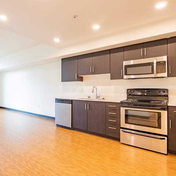 an empty kitchen with wood flooring and stainless steel appliances