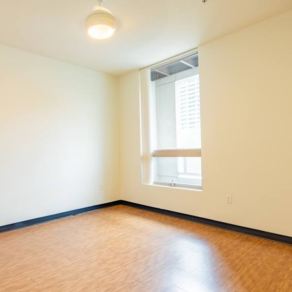 an empty room with wood flooring and a window