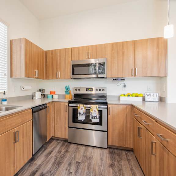 a kitchen with wooden cabinets and stainless steel appliances and a sink at villas on olive, peoria, arizona