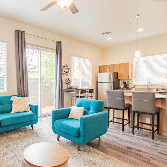 a living room with blue couches and a kitchen with a table and chairs at villas on olive, peoria, arizona