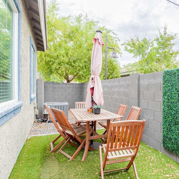 a backyard patio with a table and chairs and a privacy hedge at villas on olive, peoria, arizona 85345