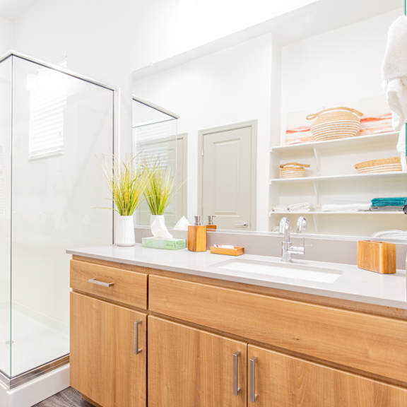 a bathroom with a shower and a sink and wooden cabinets at villas on olive, peoria, arizona