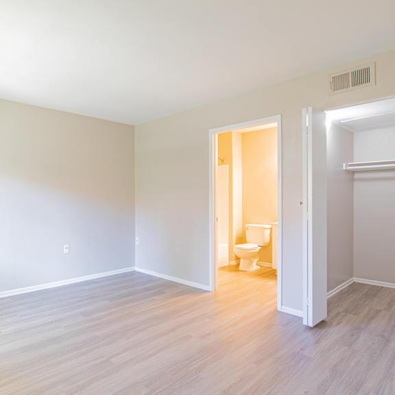 an empty living room with wood flooring and a toilet