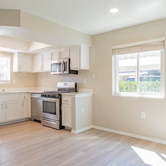 an empty kitchen with white cabinets and a window