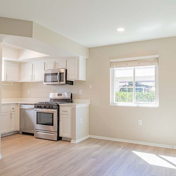 an empty kitchen with white appliances and a window