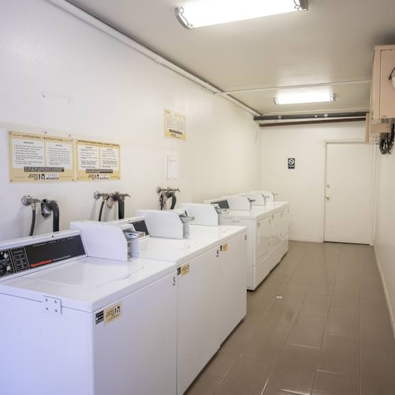 a laundry room with four washers and dryers and a row of washing machines