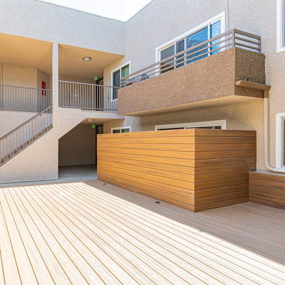 a courtyard with a wooden deck and a building with stairs