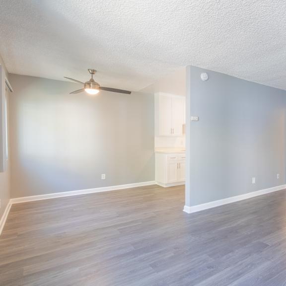 an empty living room with blue walls and a ceiling fan