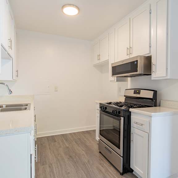 a kitchen with white cabinets and a stove and microwave