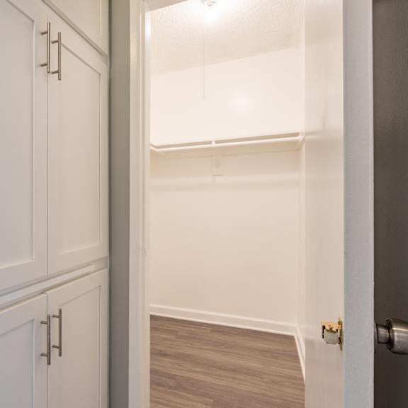 the closet in a small room with white cabinets and a door