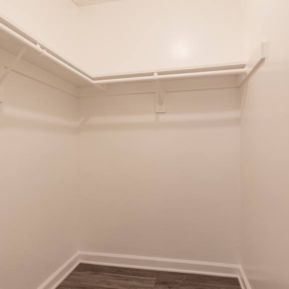 an empty room with white walls and a white shelf in the corner