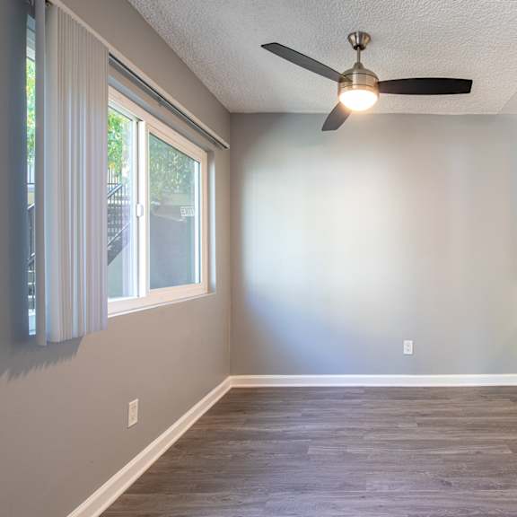 an empty kitchen with white cabinets and a ceiling fan