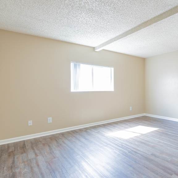 an empty living room with wood floors and a window