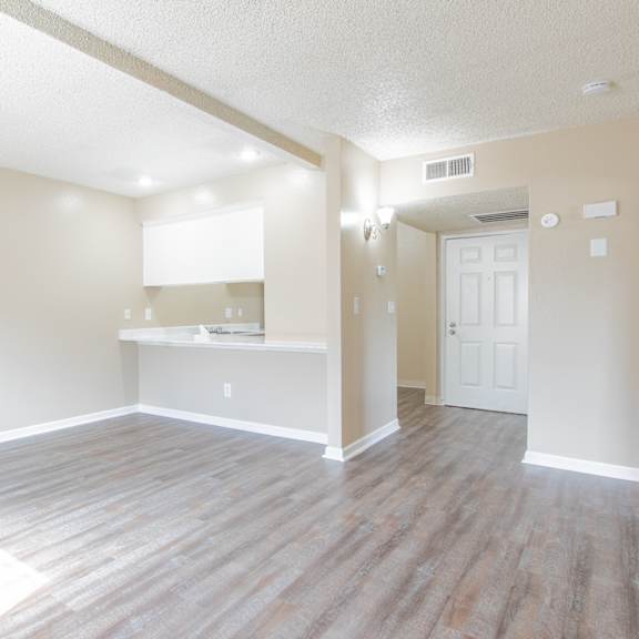 an empty living room and kitchen with wood flooring