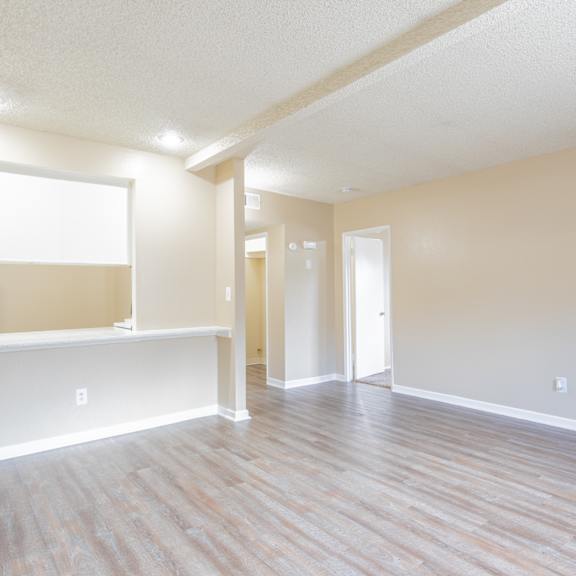 an empty living room and kitchen with a wood floor