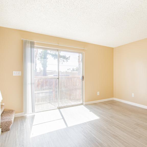 an empty living room with a sliding glass door to a patio