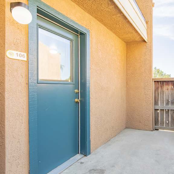 the balcony has a blue door and a wooden fence
