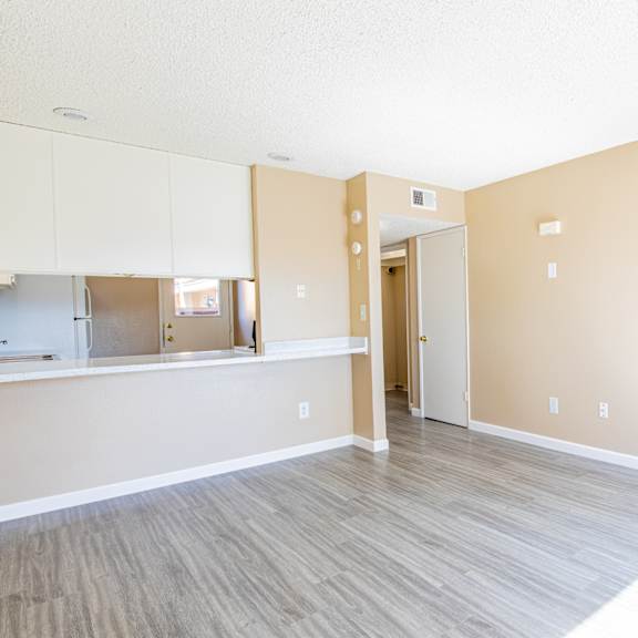 an empty living room with a staircase and a kitchen