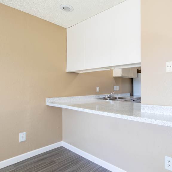 an empty kitchen with white cabinets and a counter top