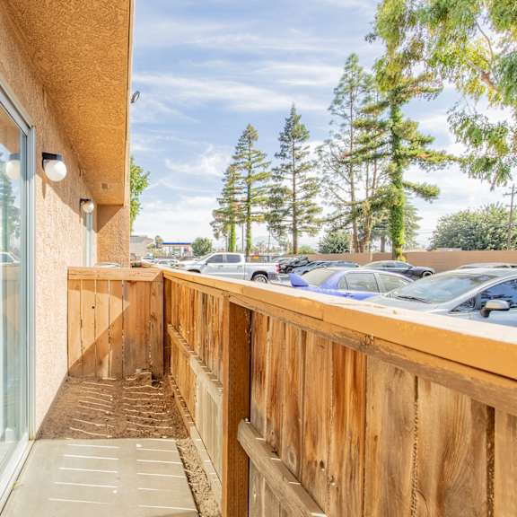 the balcony has a wood railing and a glass door