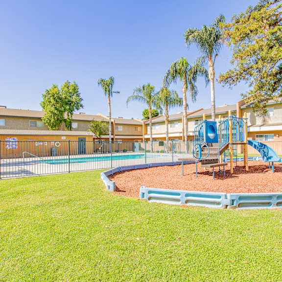 a playground with a blue playset in the grass