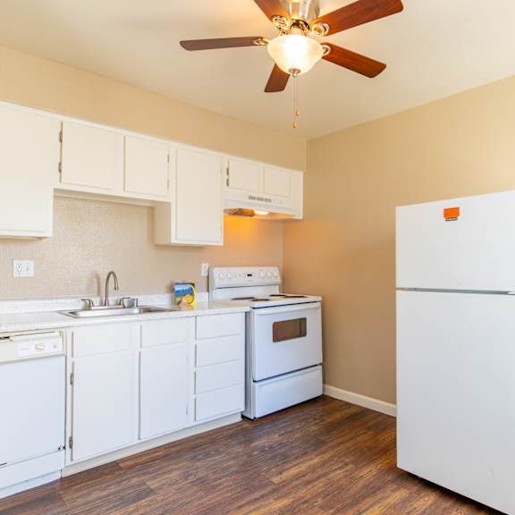 a kitchen with white appliances and a ceiling fan