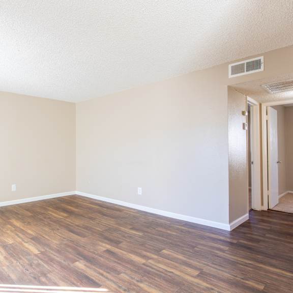 an empty living room with a hard wood floor and white walls