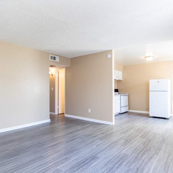 an empty living room and kitchen with a refrigerator and