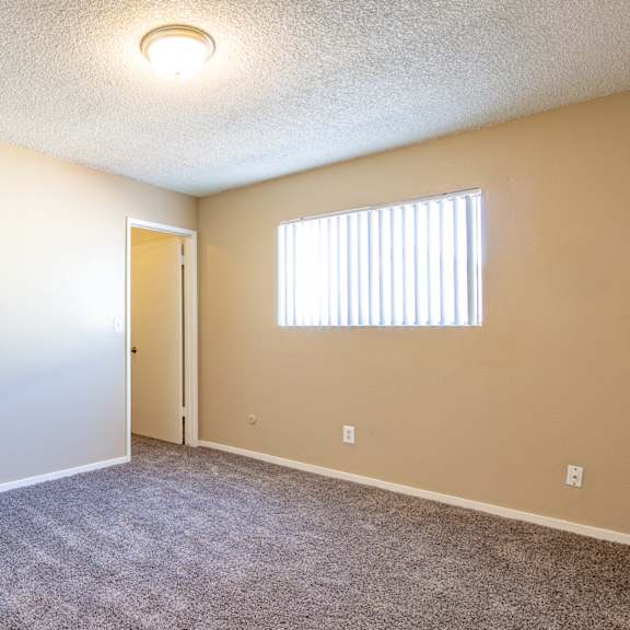 an empty living room with a door to a hallway and a window